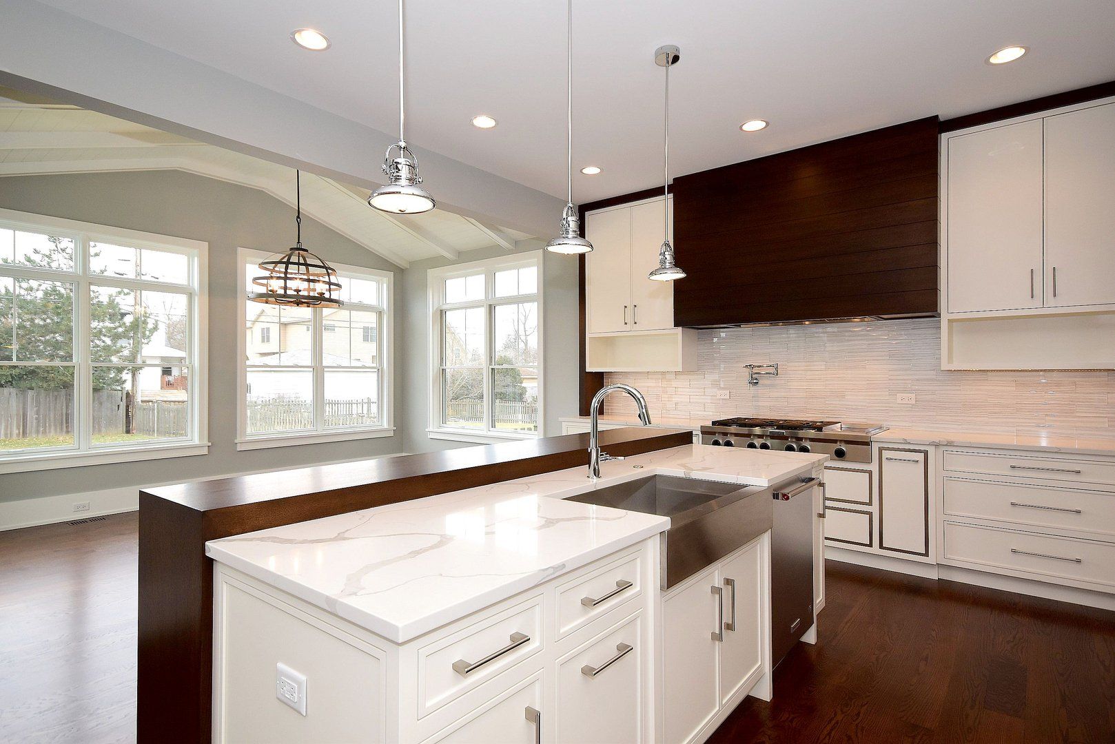A kitchen with white cabinets and a large island with a sink.