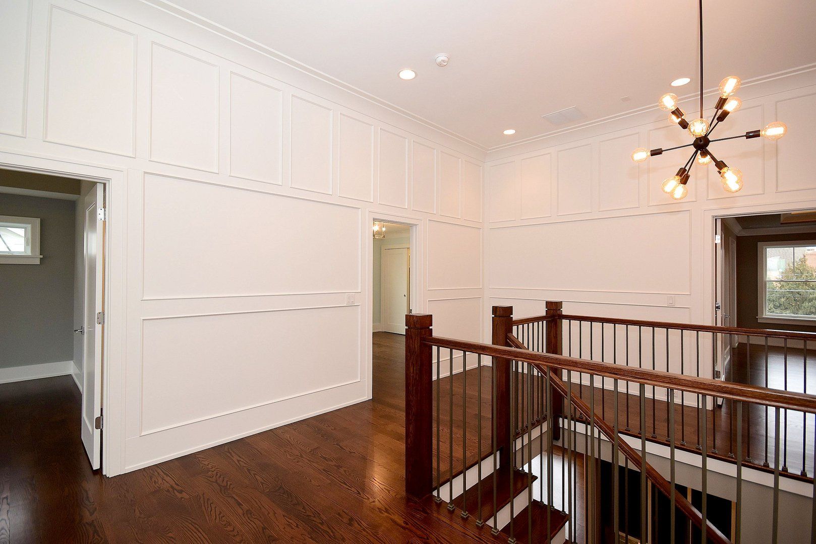 An empty hallway with stairs and a chandelier in a house.