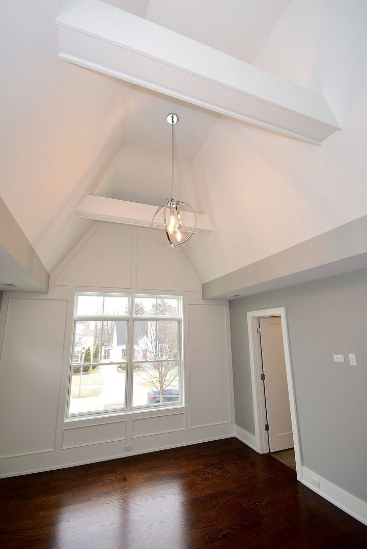 An empty room with a vaulted ceiling and a chandelier