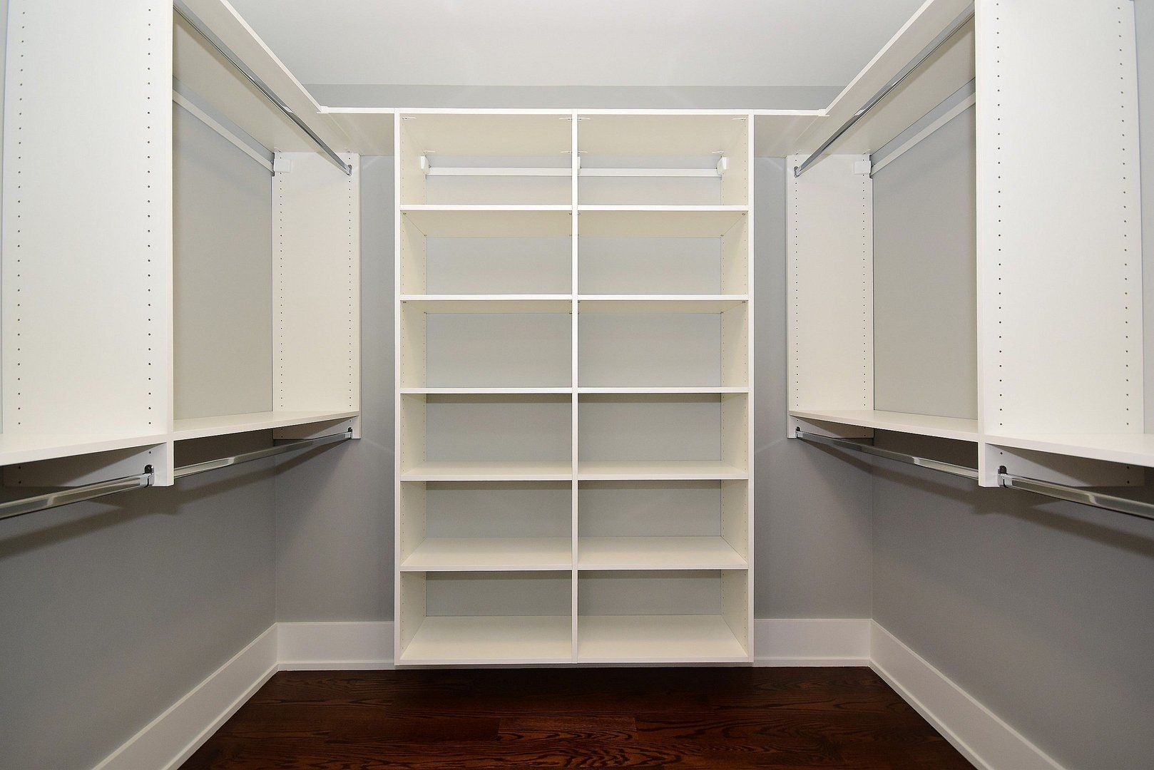 A walk in closet with lots of shelves and hanging racks.