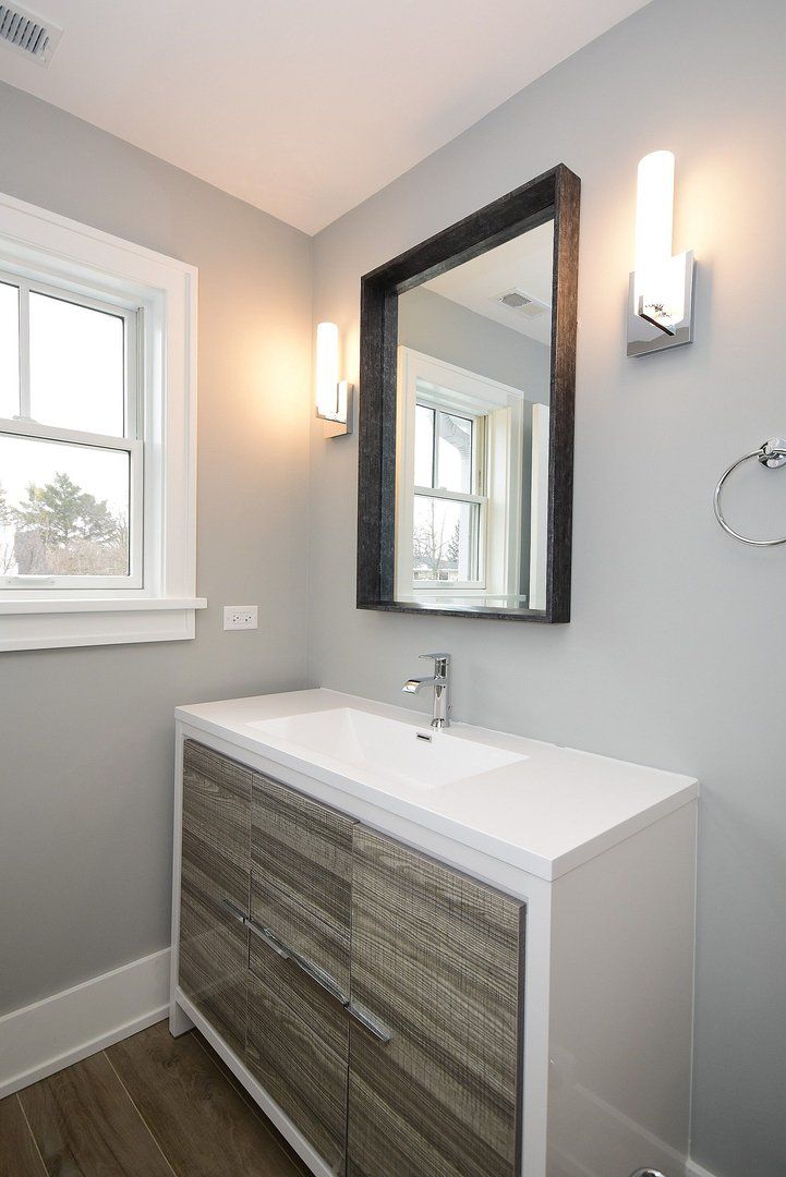 A bathroom with a sink , mirror and window.