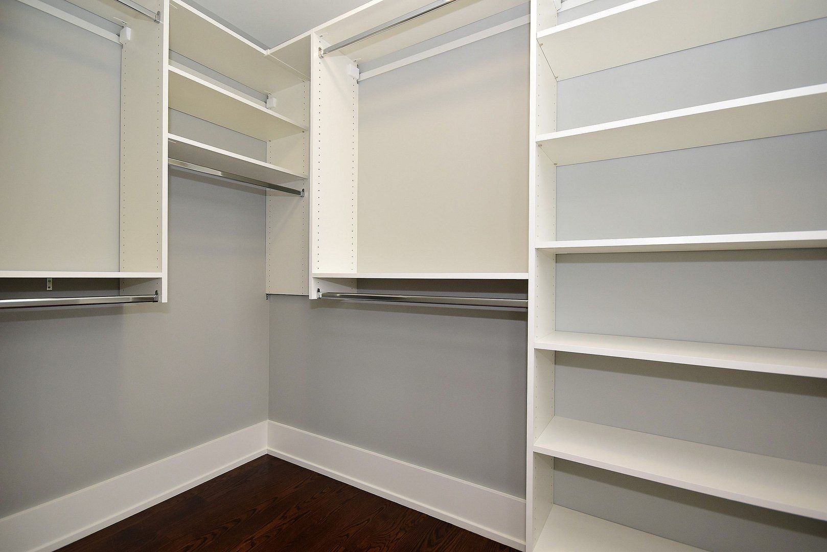 A walk in closet with lots of shelves and hanging racks.