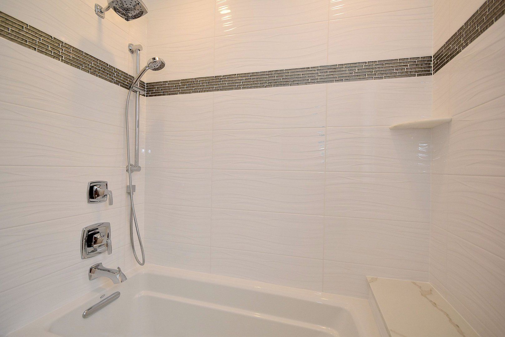 A bathroom with white tiles and a bathtub and shower.