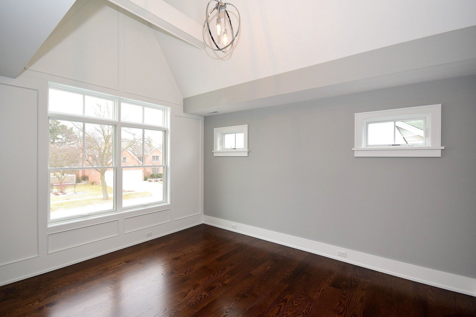 An empty room with a vaulted ceiling and two windows