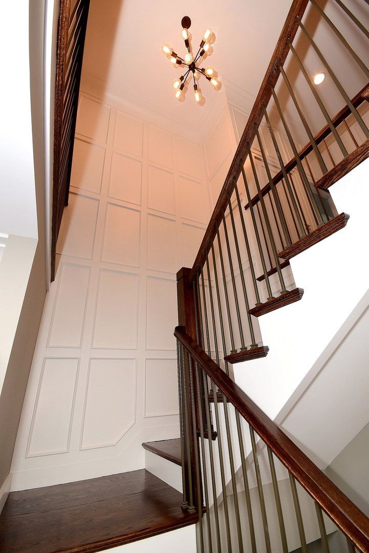 Looking up at a staircase with a chandelier hanging from the ceiling