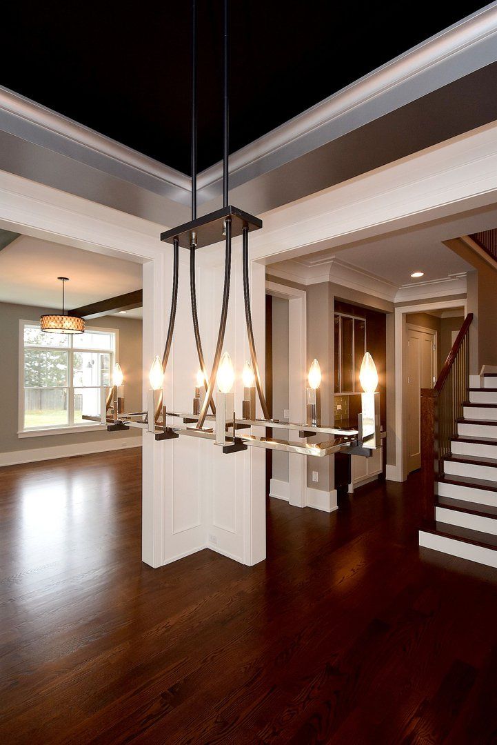 An empty room with stairs and a chandelier hanging from the ceiling