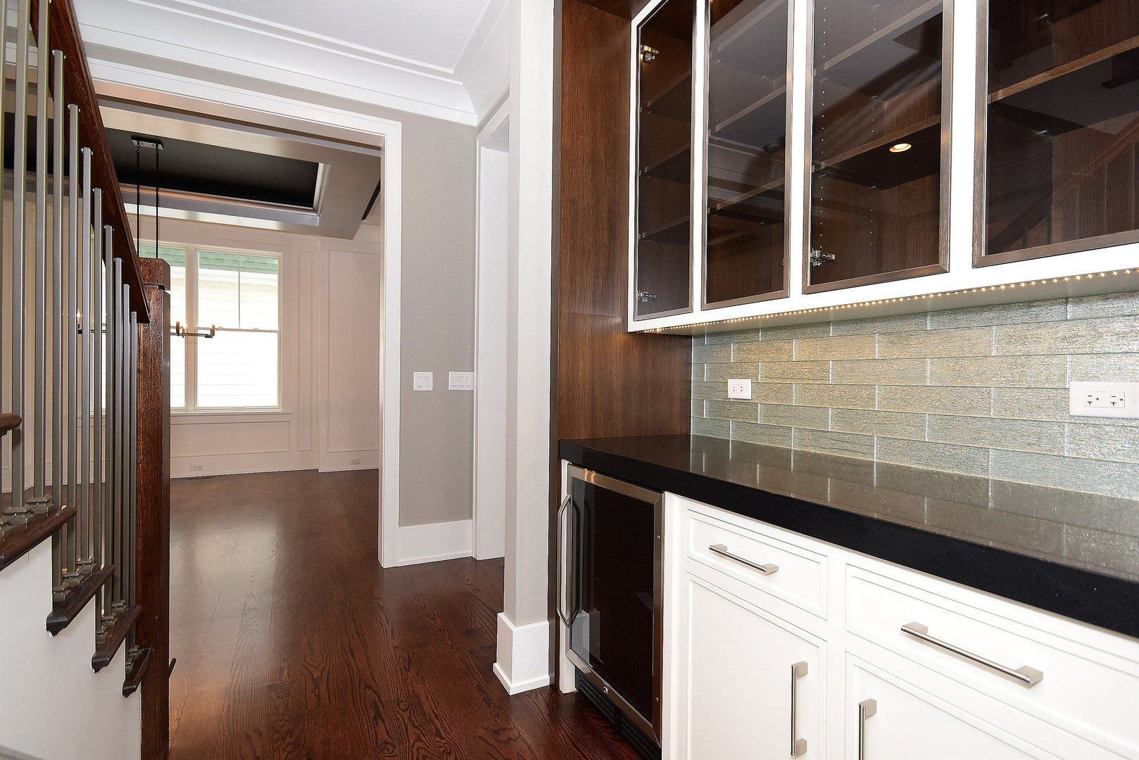 A kitchen with hardwood floors , white cabinets and a refrigerator.