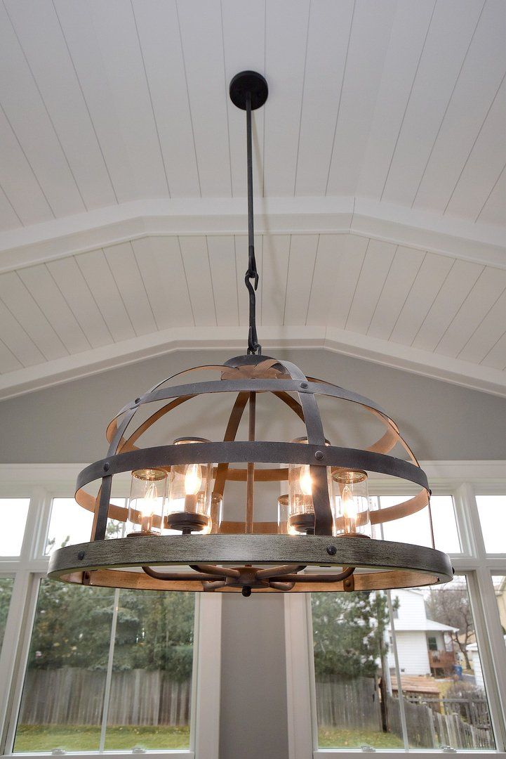 A chandelier is hanging from the ceiling in a room with a lot of windows.