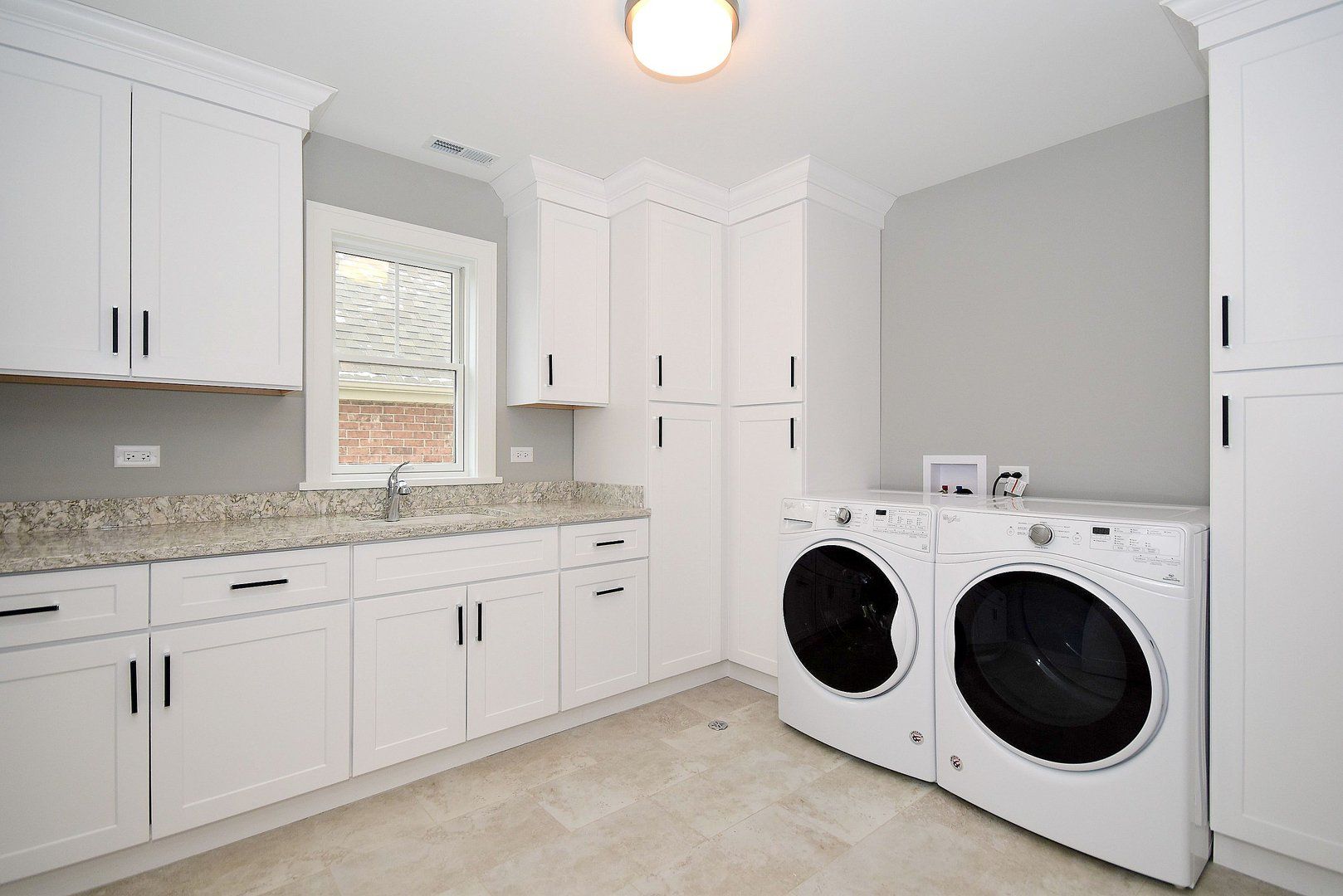 A laundry room with a washer and dryer and white cabinets