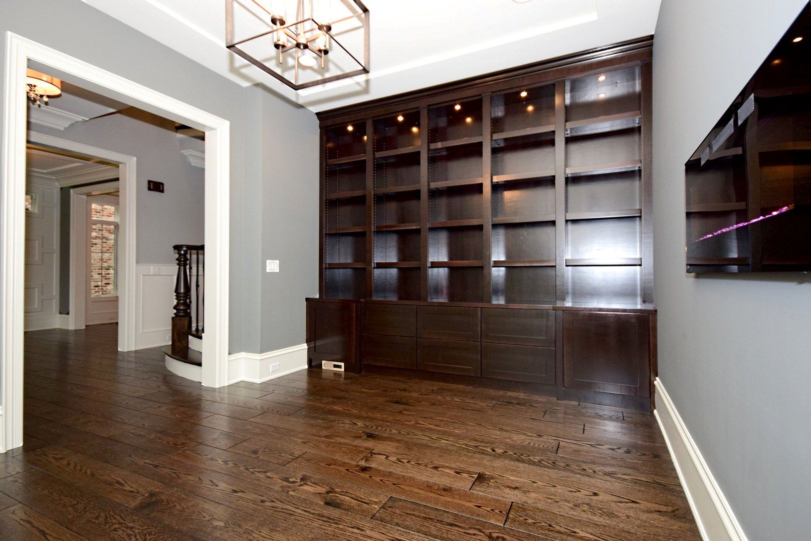An empty room with a large bookcase and a flat screen tv on the wall