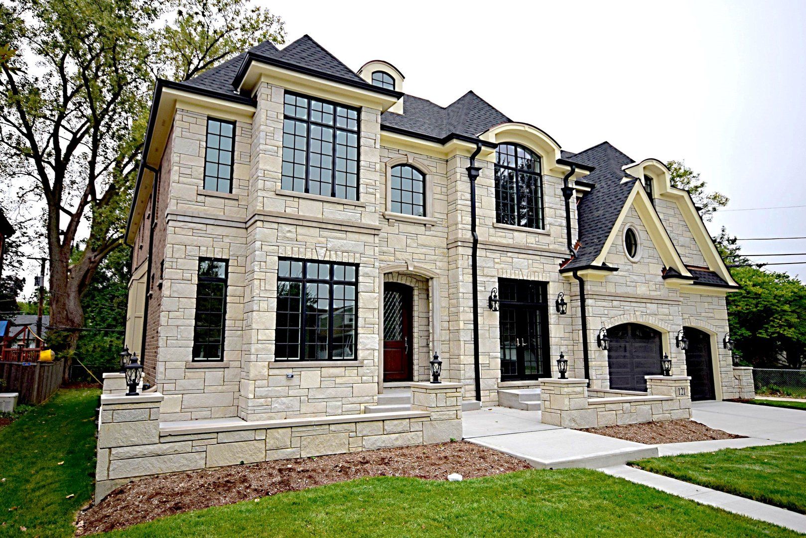 A large brick house with a black roof is sitting on top of a lush green lawn.