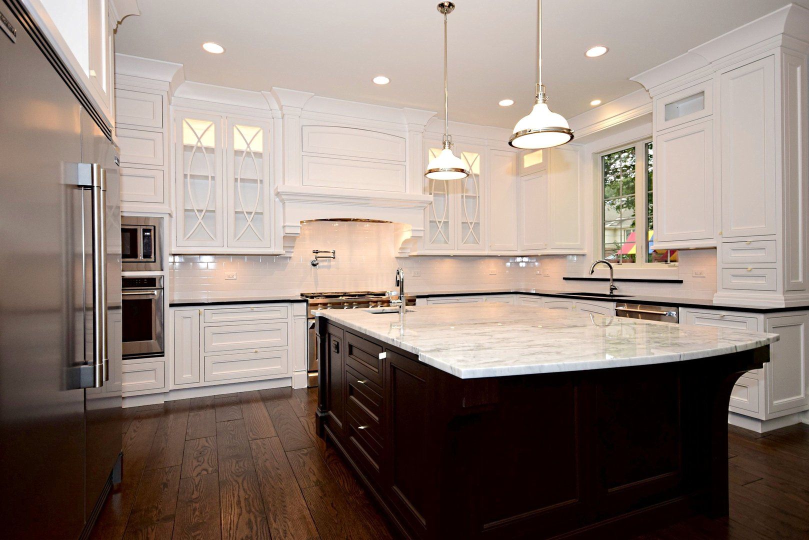 A kitchen with white cabinets and a large island in the middle