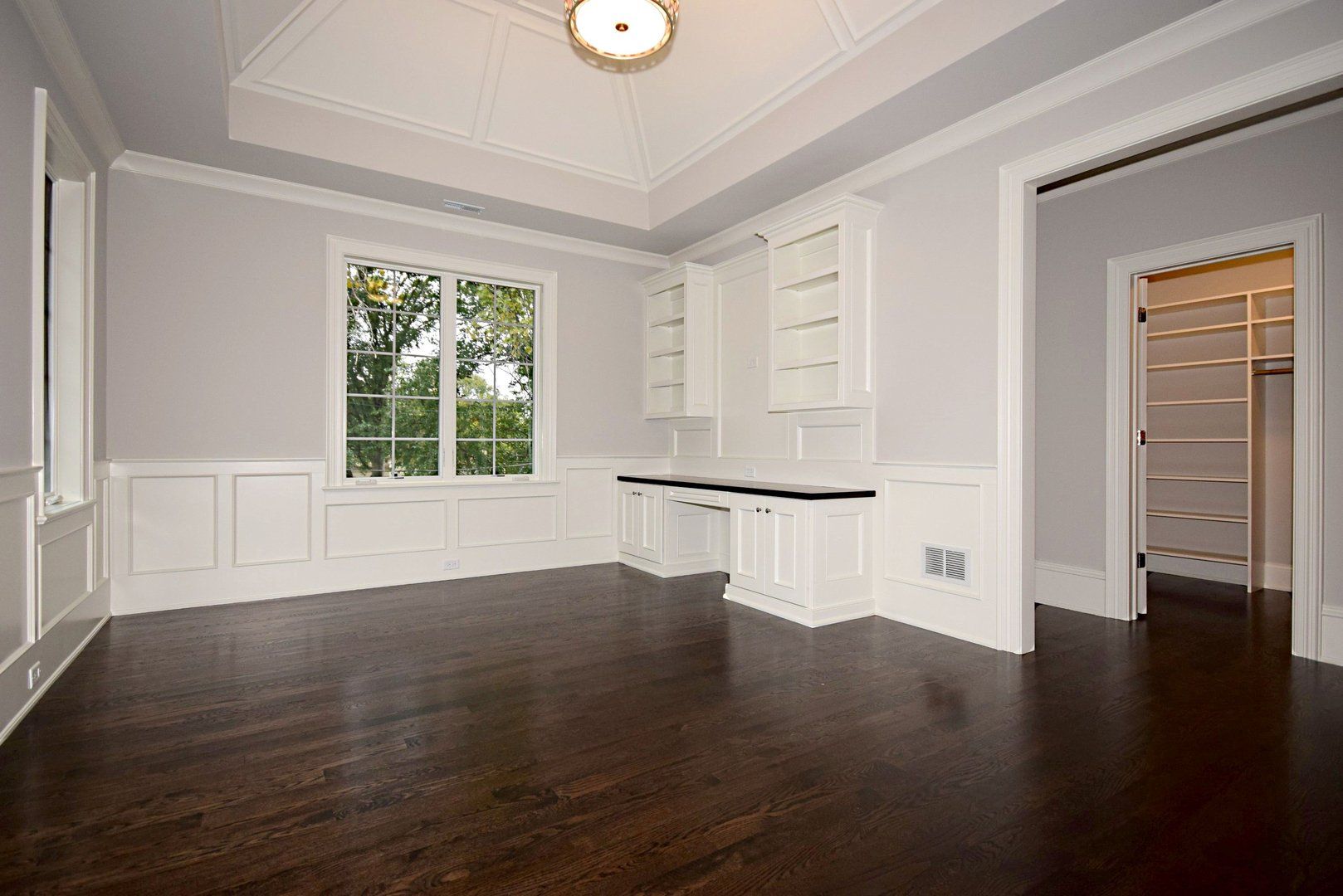 A large empty room with hardwood floors and white walls.