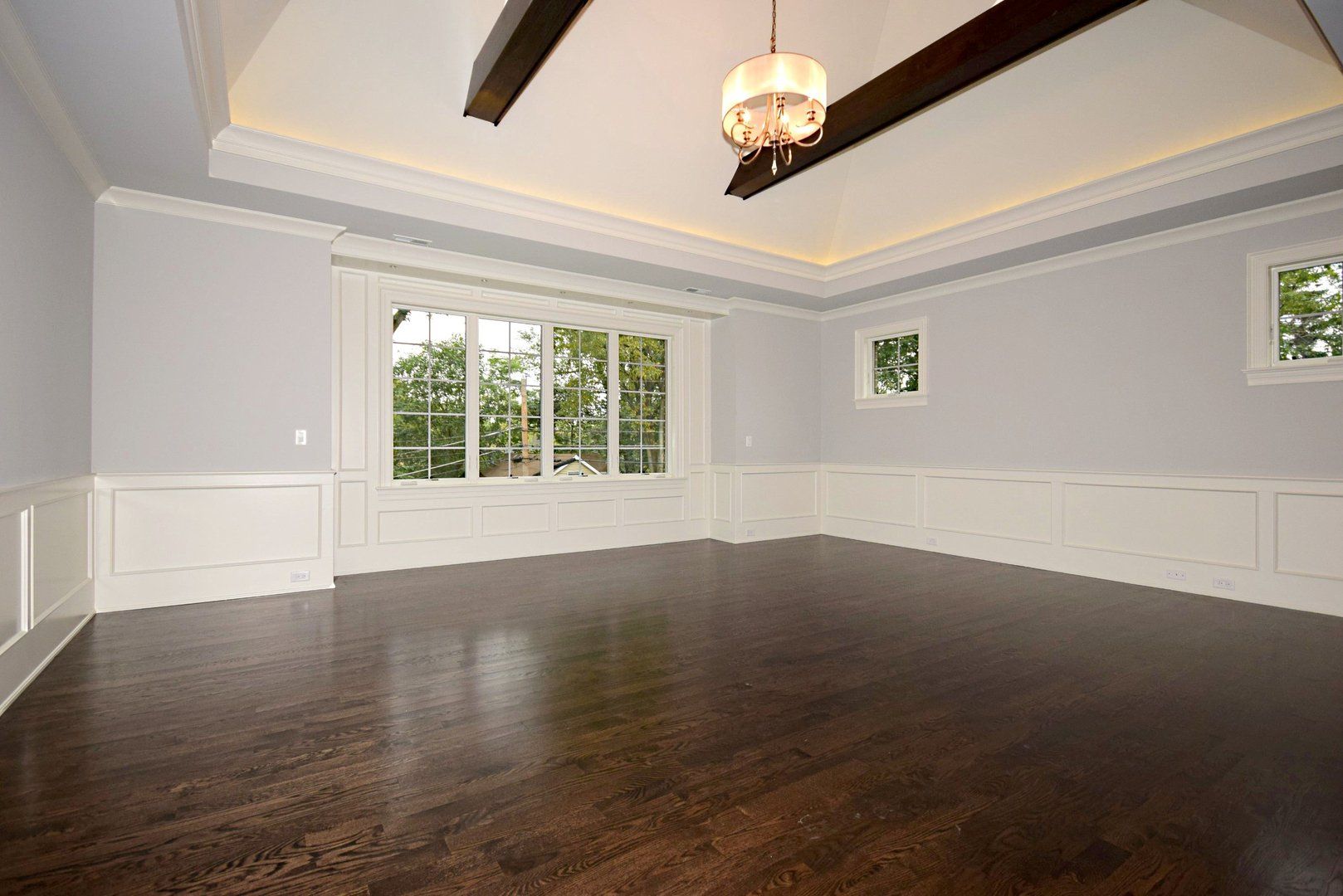 An empty room with a large window and a chandelier