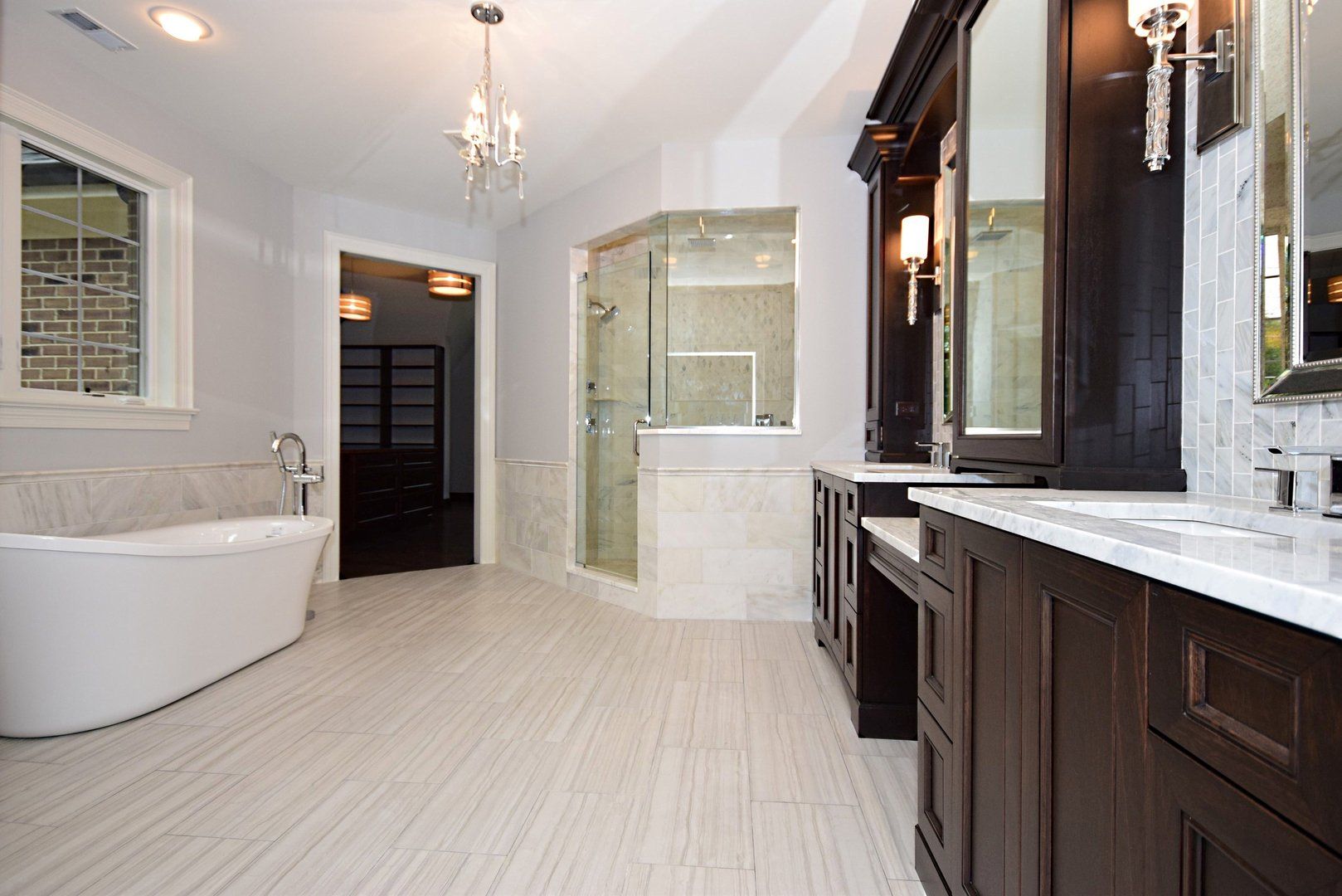 A bathroom with a tub , sinks , mirrors and a walk in shower.
