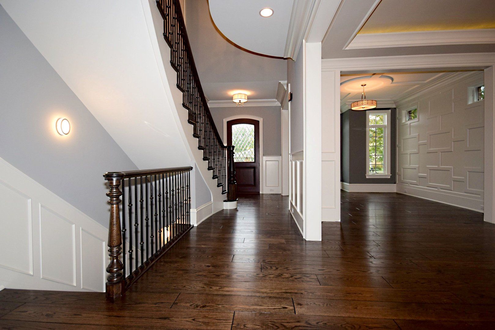 An empty hallway with a curved staircase and wooden floors