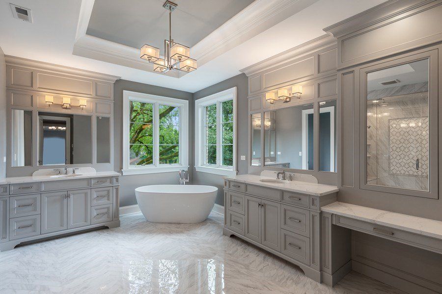 A bathroom with a tub , sinks , mirrors and a chandelier.