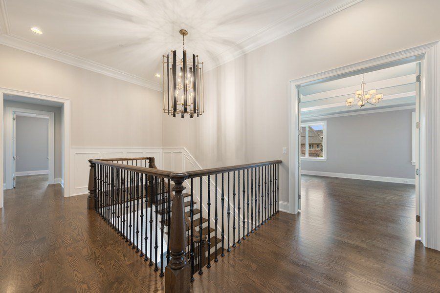 A staircase in a house with a wooden railing and a chandelier.