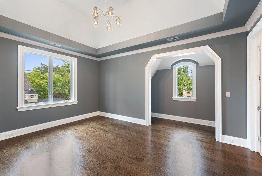 An empty living room with gray walls and hardwood floors.