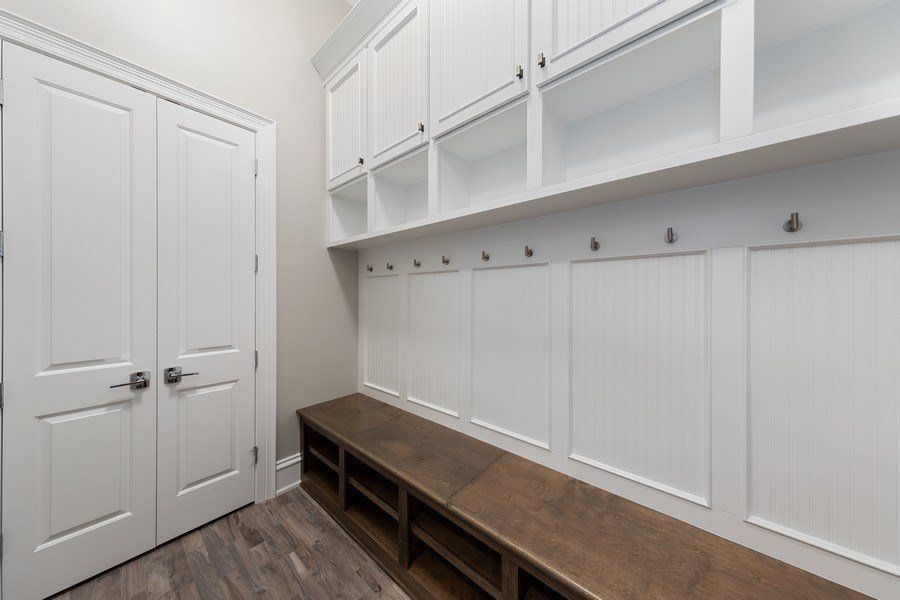 A mud room with white cabinets and wooden benches.