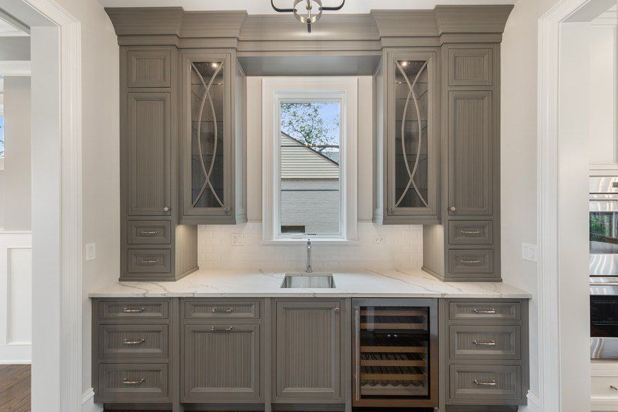 A kitchen with gray cabinets and a wine cooler.