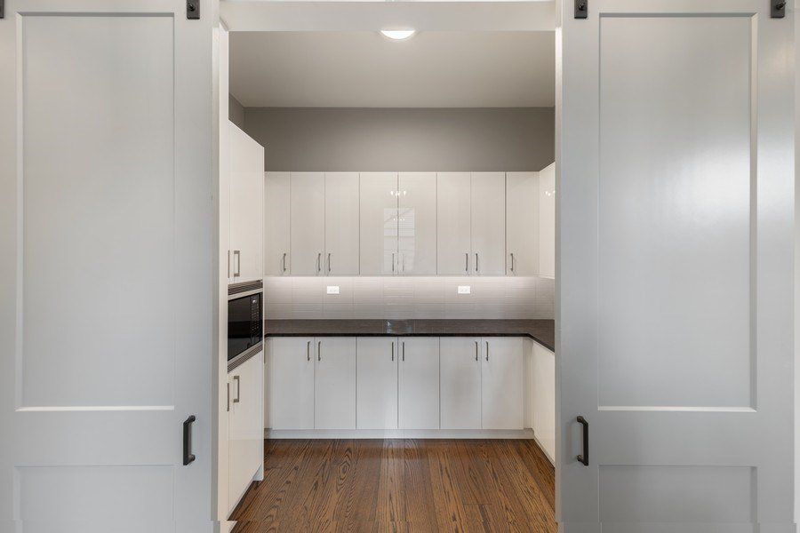 A kitchen with white cabinets and wooden floors and sliding barn doors.