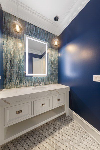 A bathroom with blue walls and a sink and mirror