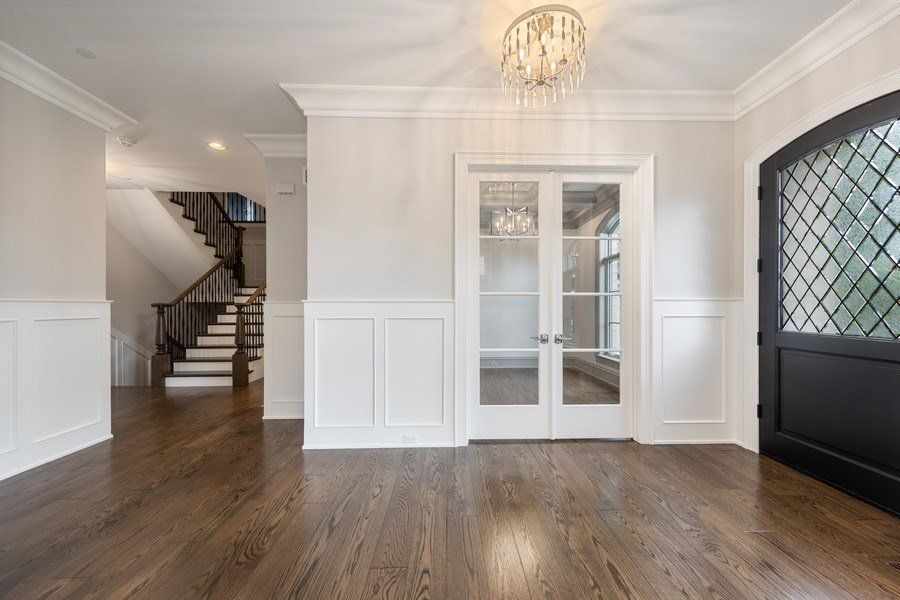 A large empty room with hardwood floors and a staircase in the background.