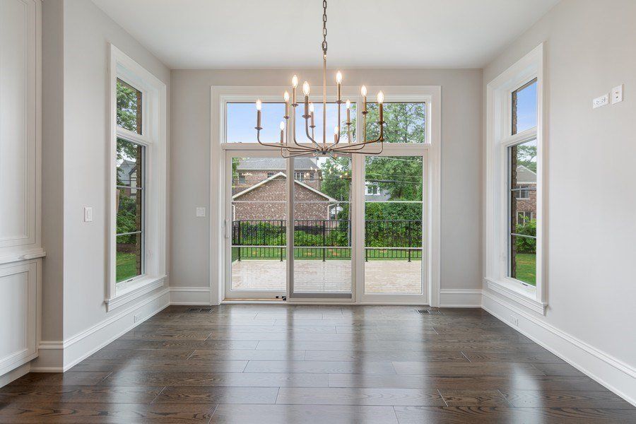 An empty dining room with hardwood floors and a chandelier.