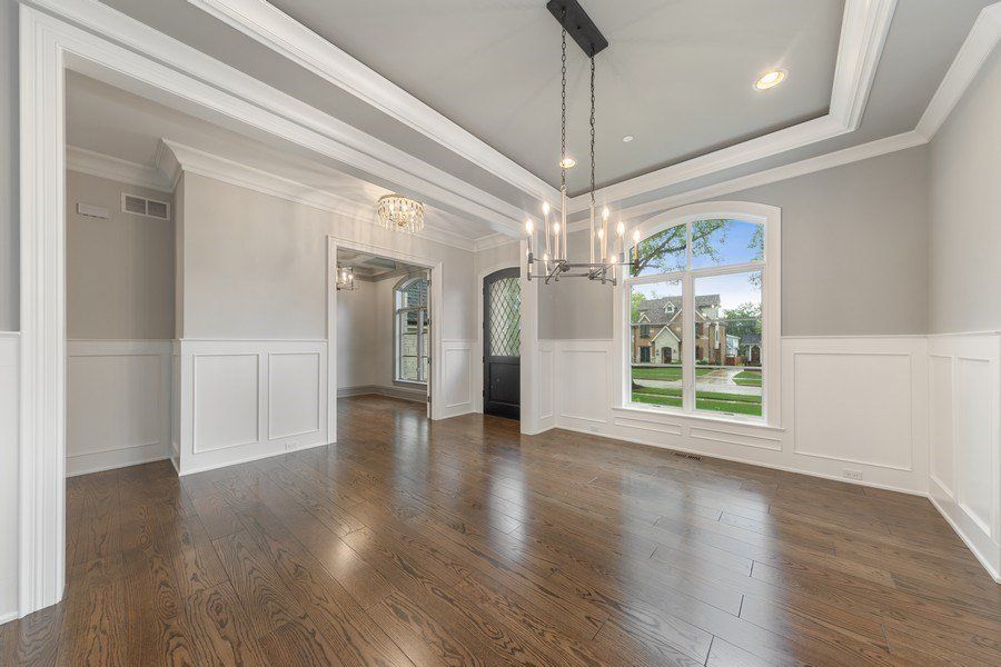 An empty dining room with hardwood floors and a chandelier.