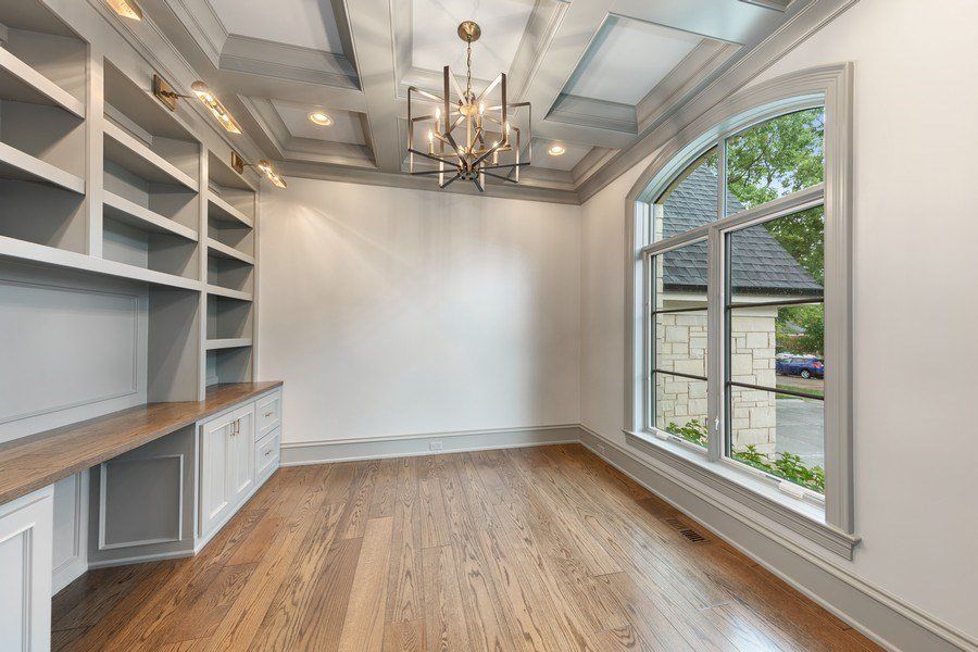 A large empty room with hardwood floors and a chandelier.