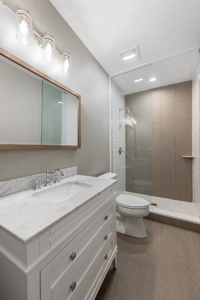 A bathroom with a sink , toilet , shower and mirror.