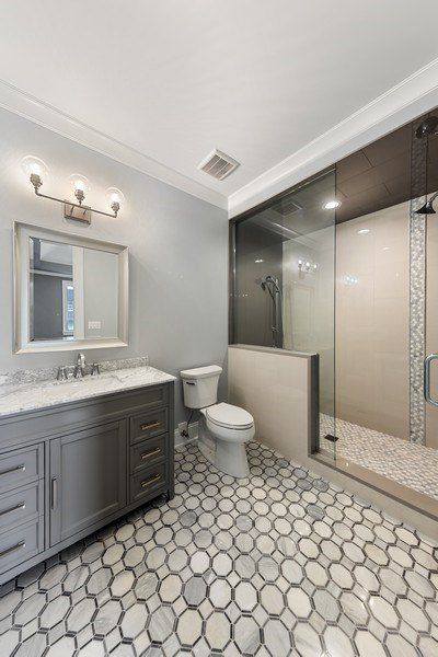 A bathroom with a toilet , sink , mirror and walk in shower.