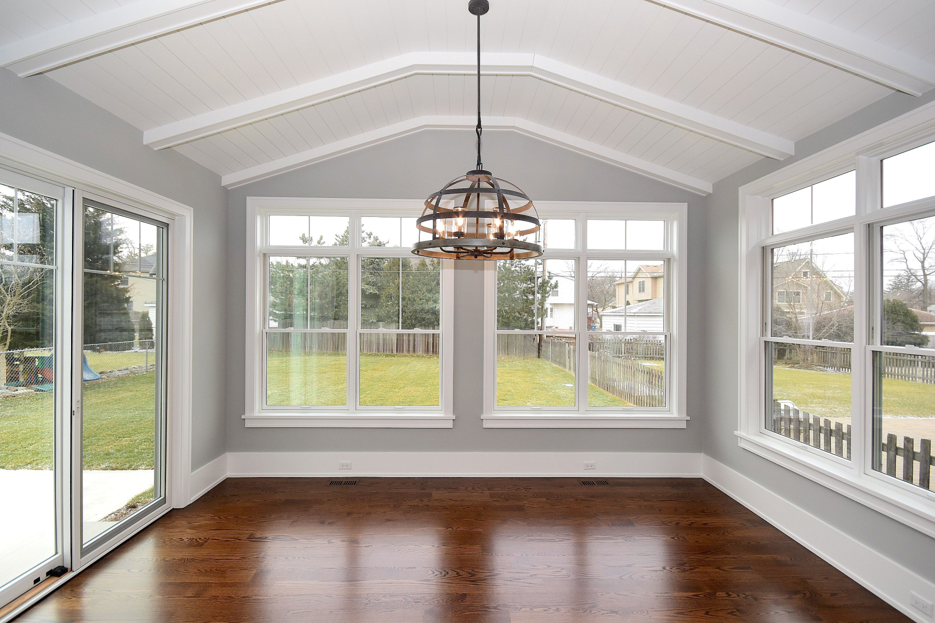 An empty room with lots of windows and a chandelier