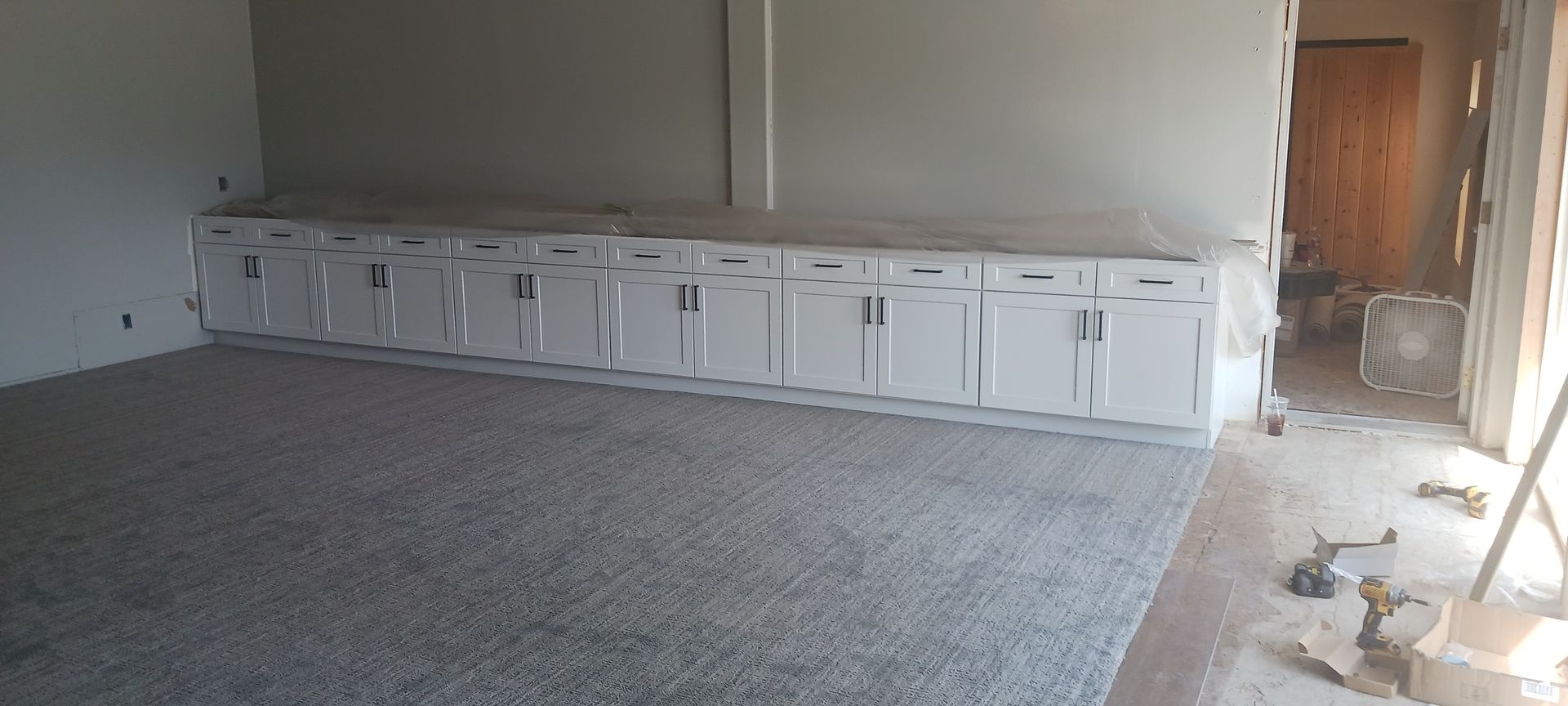 An empty room with a lot of cabinets and a carpeted floor.