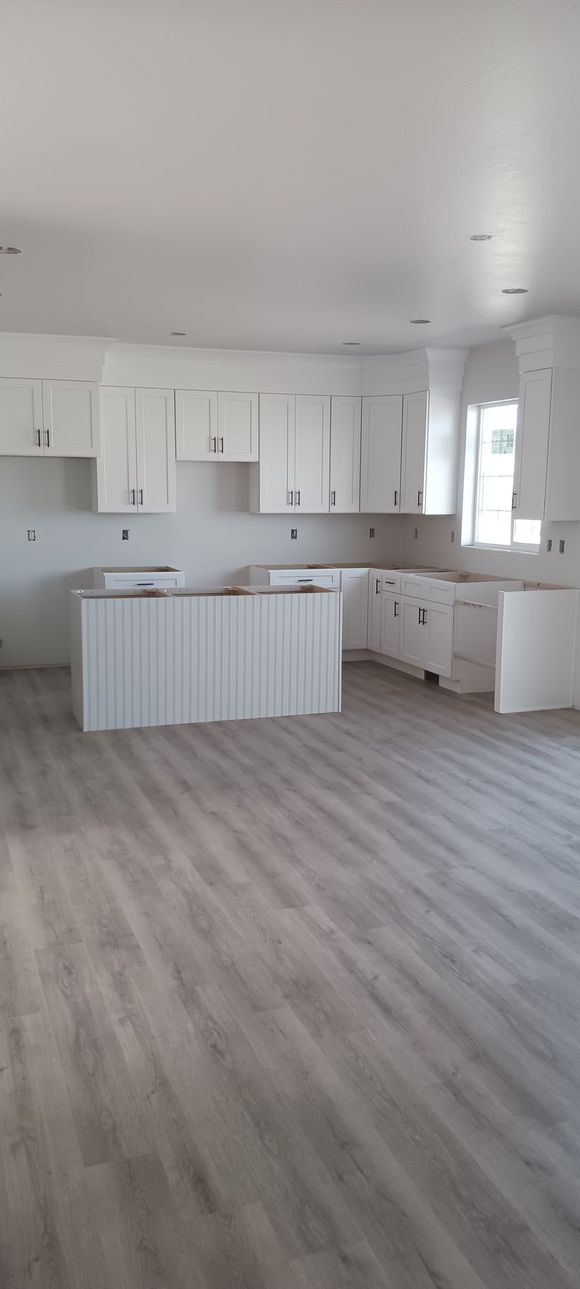 An empty kitchen with white cabinets and a large island.