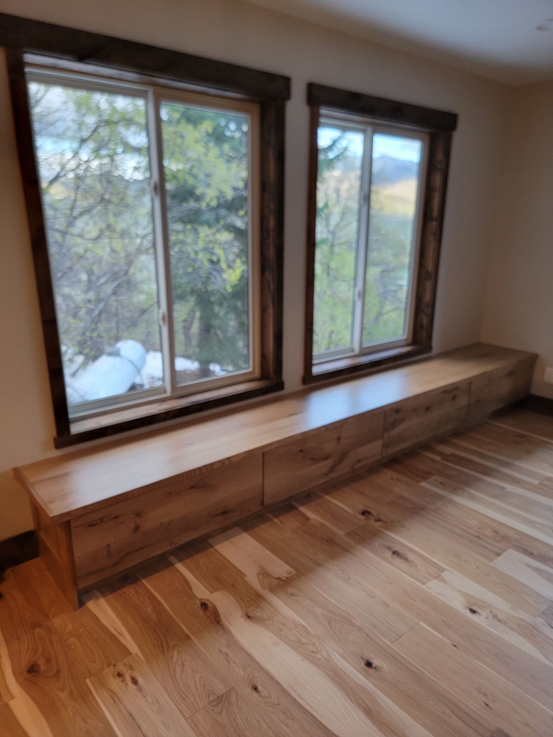 A room with two windows and a wooden bench