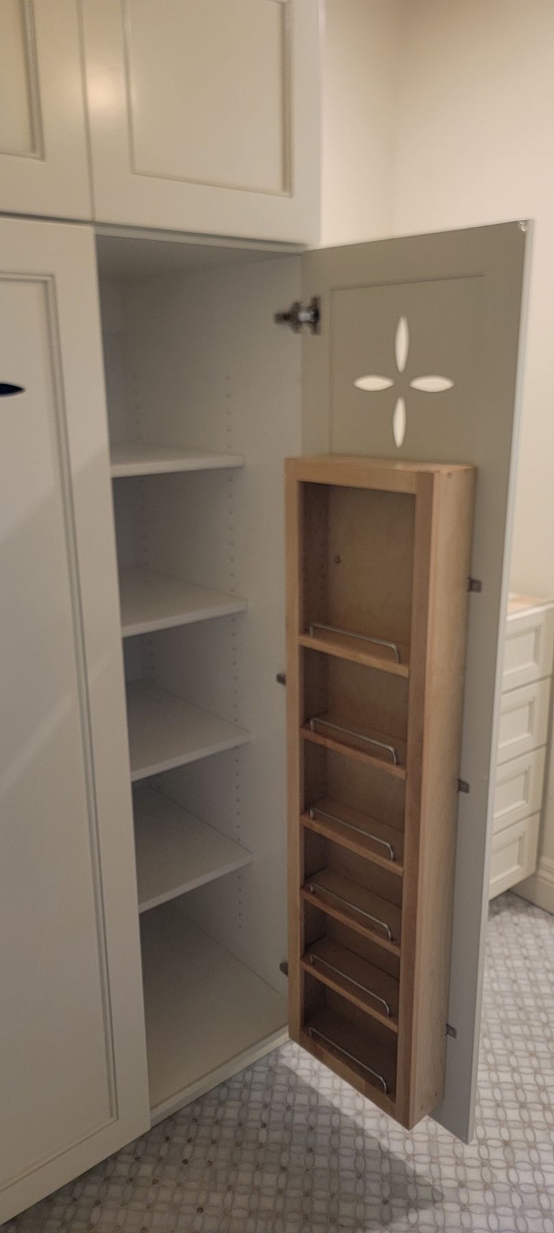 A white cabinet with a wooden spice rack inside of it.
