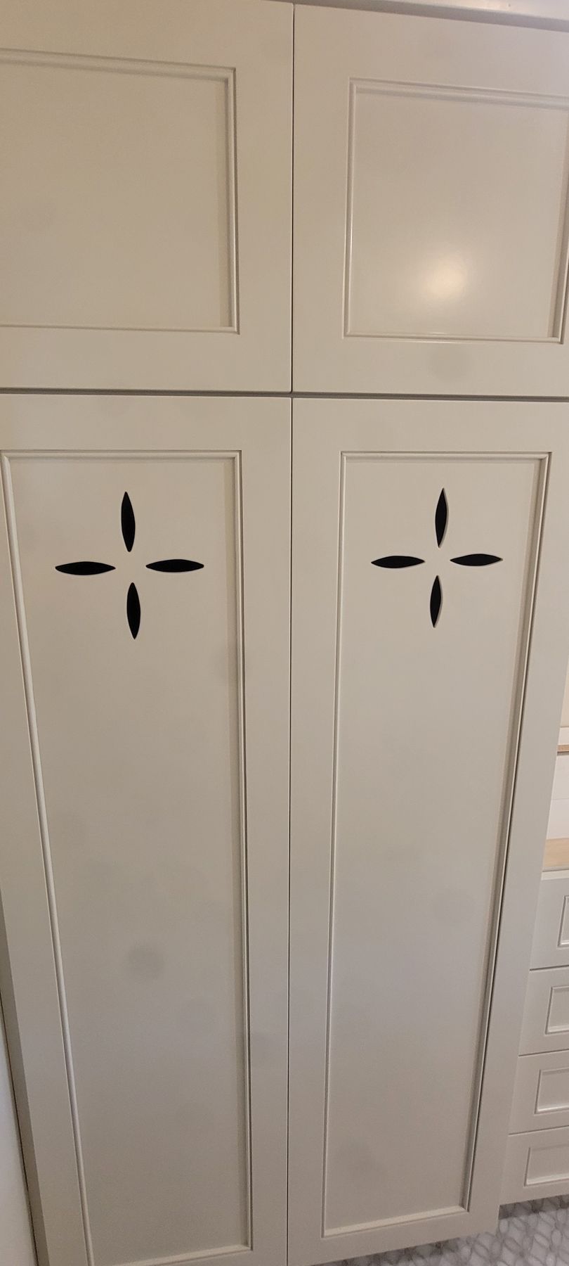 A close up of a white cabinet with a cross on the door.