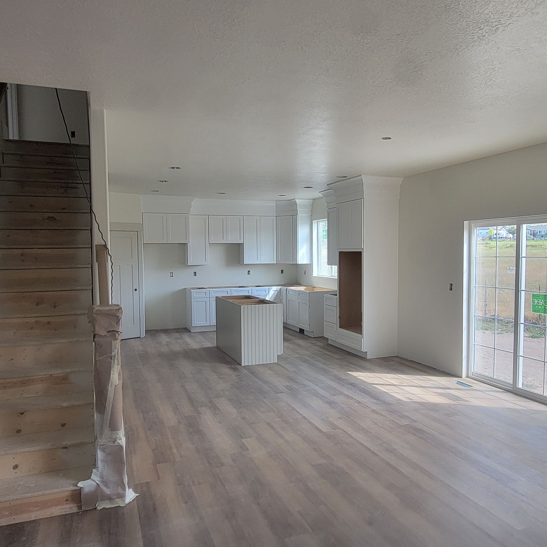 A large empty room with a kitchen and stairs
