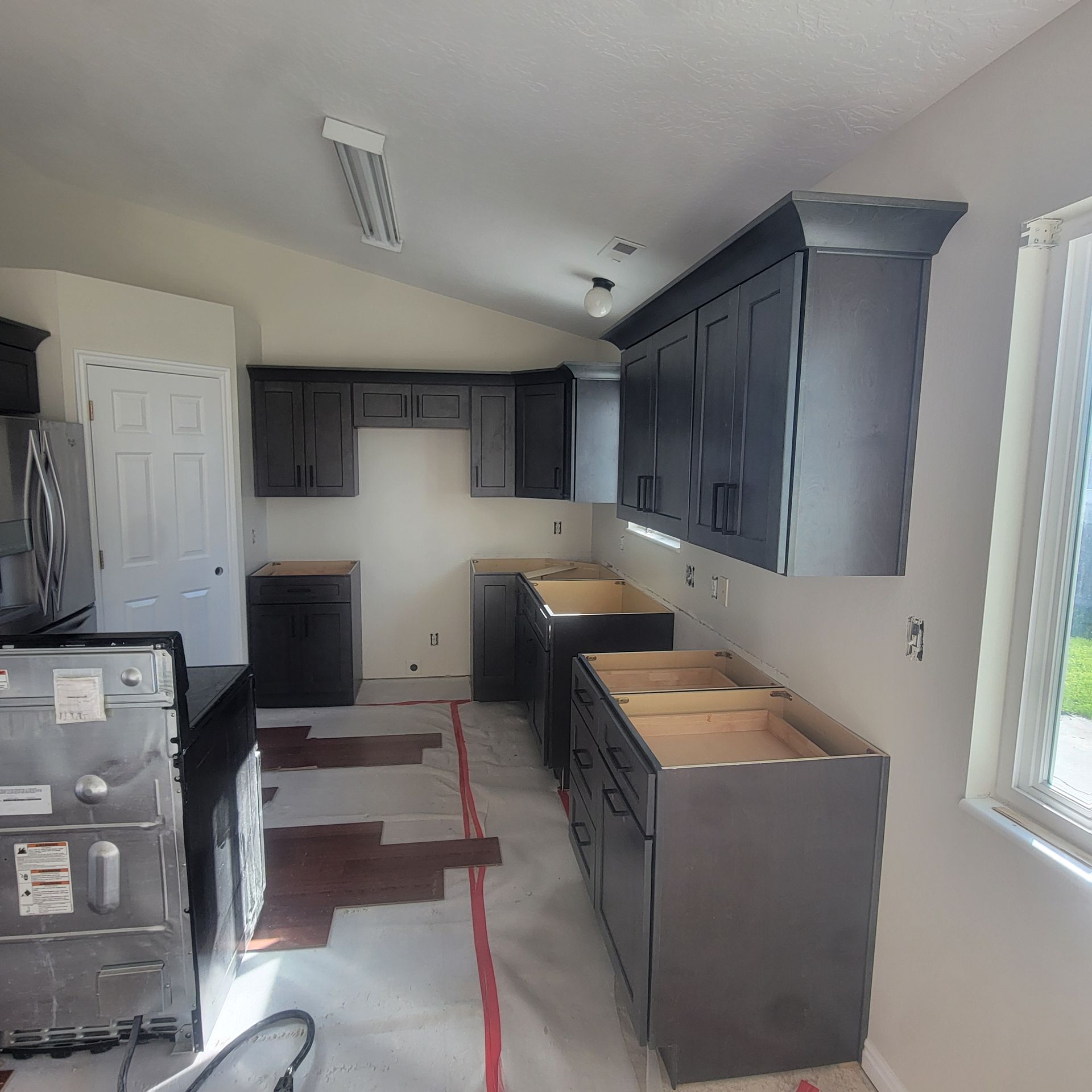 A kitchen is being remodeled with black cabinets and a dishwasher.