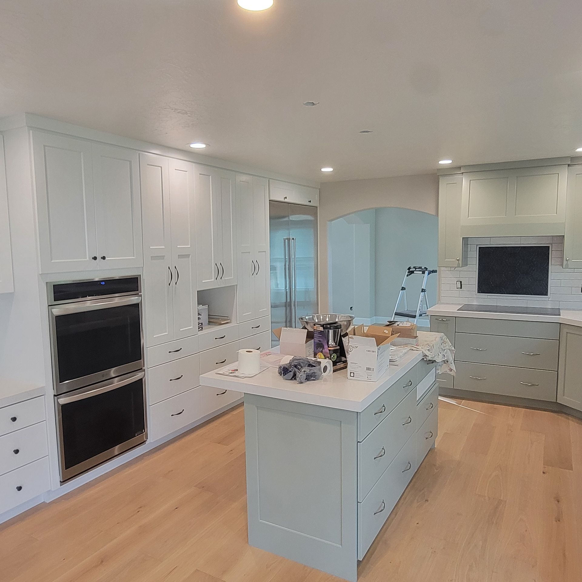 A kitchen with white cabinets and a large island in the middle