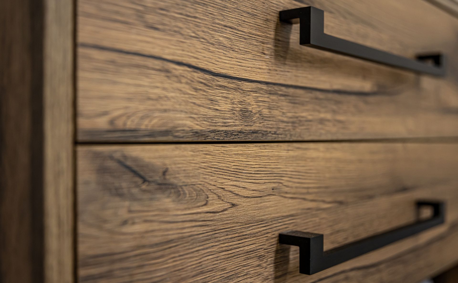 Close-up of a wooden dresser with dark hardware, showcasing the wood grain.