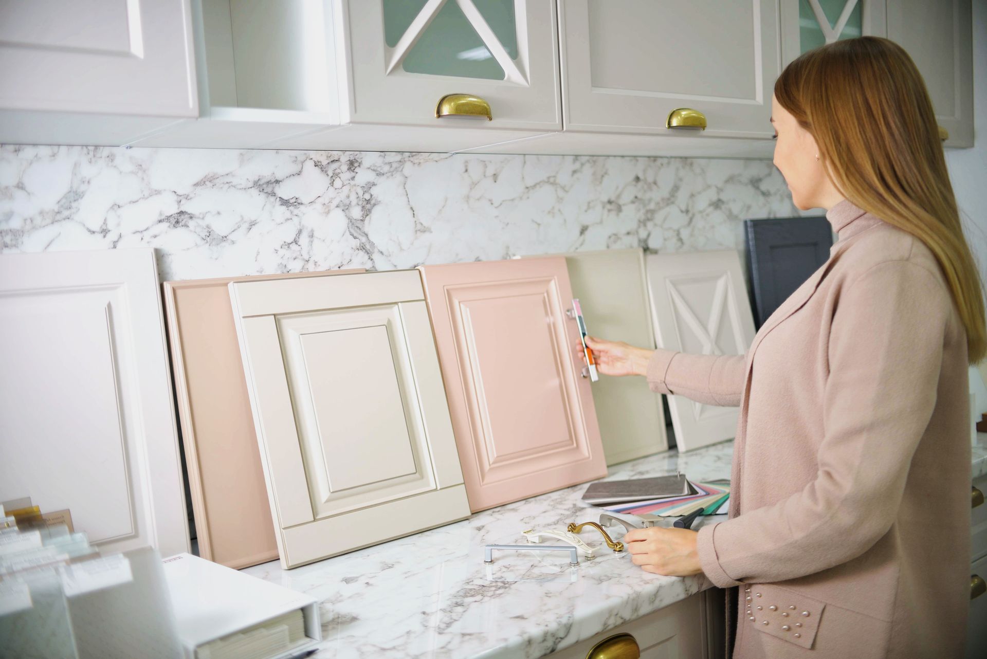 Woman selecting cabinet door color samples in a kitchen showroom.