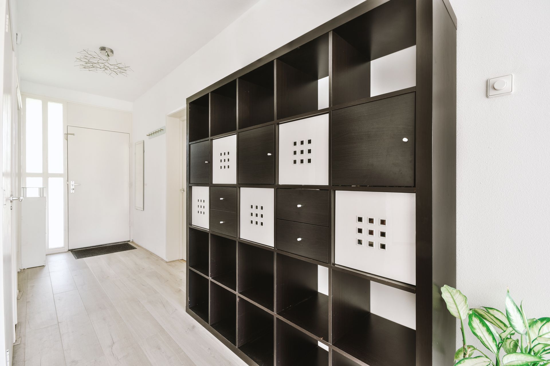 Black and white cube storage unit in hallway, with white walls and a door in the background.