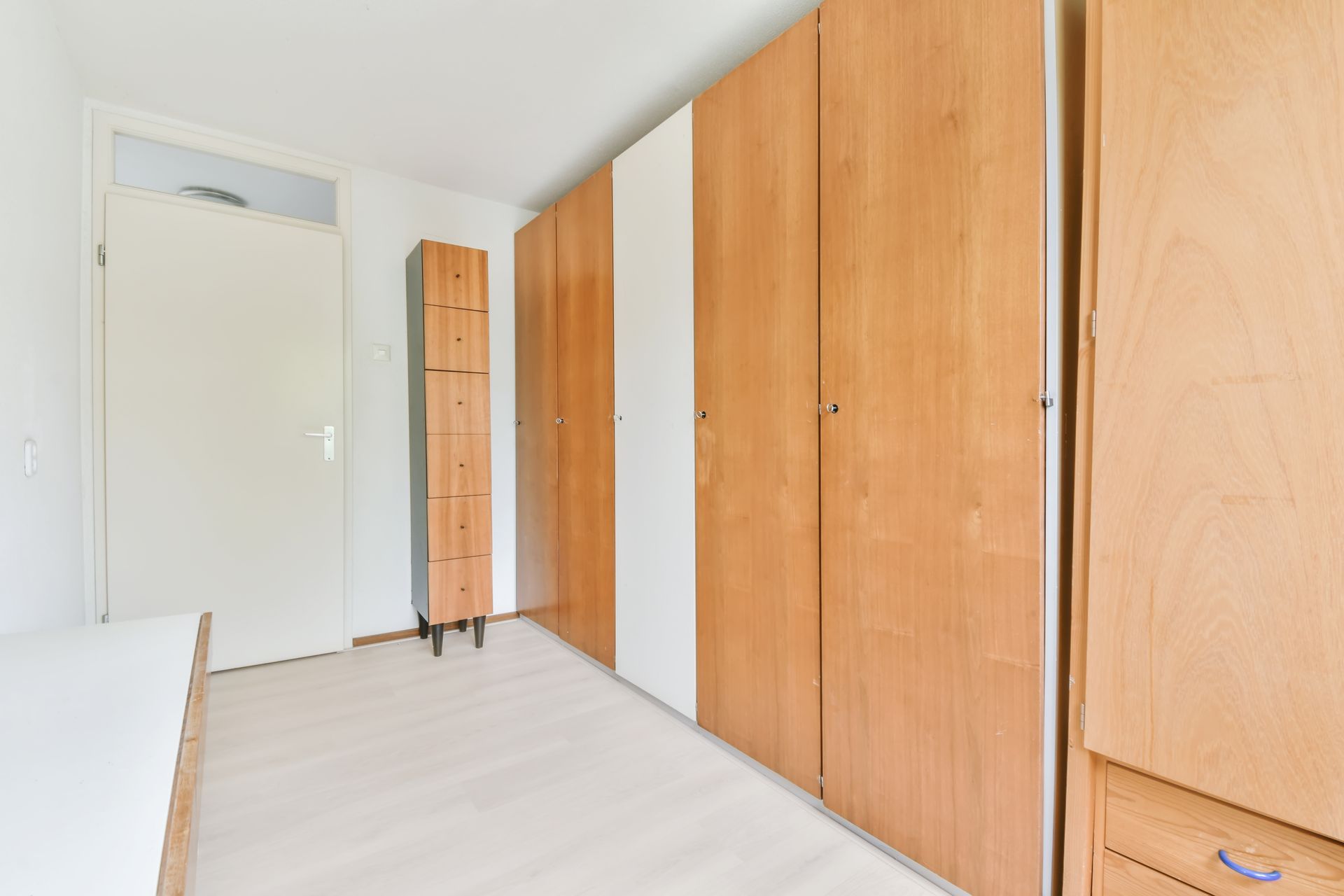 A bedroom with a lot of wooden cabinets and drawers.