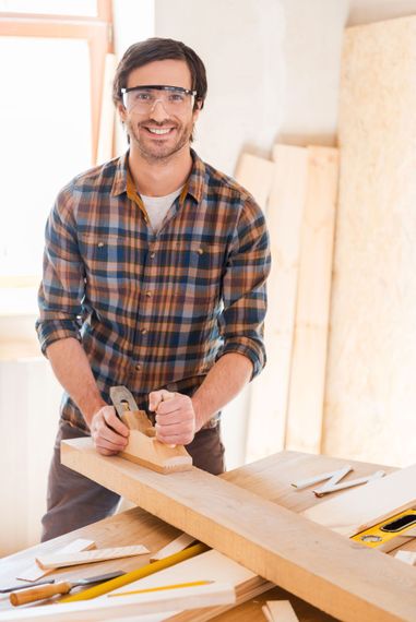 A man is using a plane to plane a piece of wood.