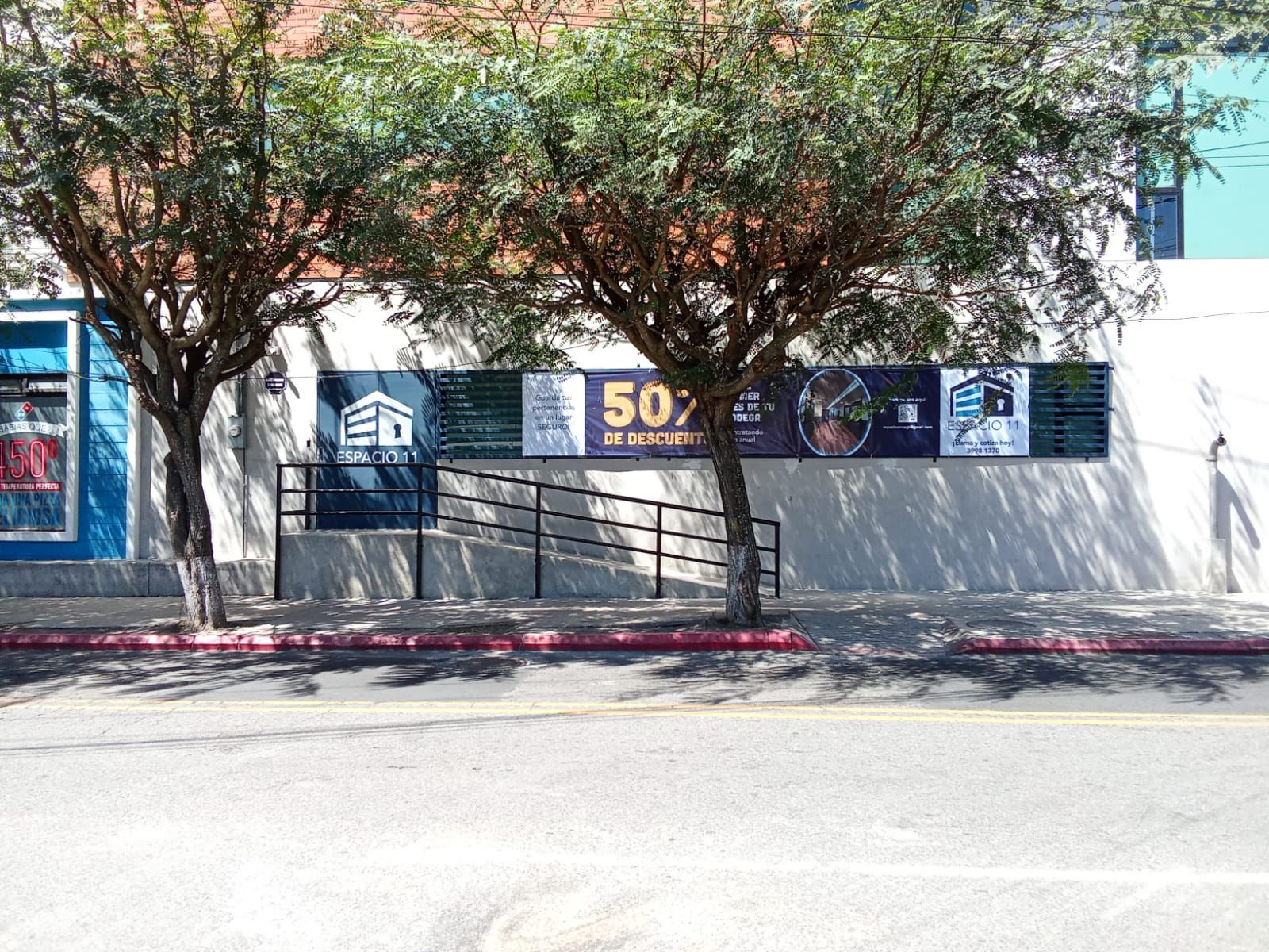 Pasillo del almacén con cajas apiladas y un expositor de globos. Logotipo de Espacio 11 en la pared.