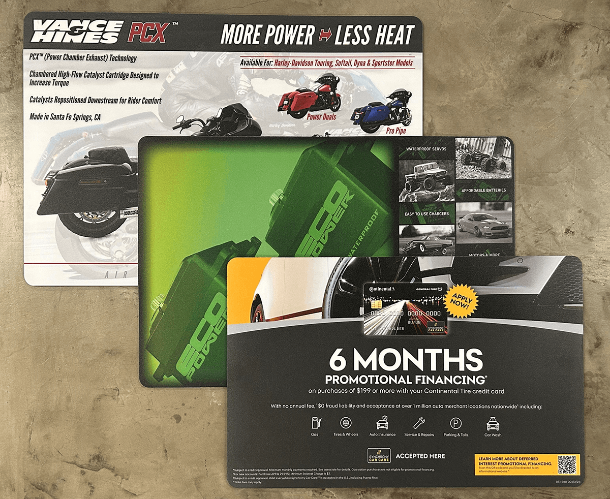 Three motorcycle-related promotional mousepads: black with text, green battery-like images, and red/blue motorcycle graphic.