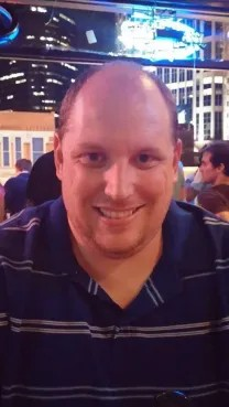 A man in a blue striped shirt is smiling for the camera